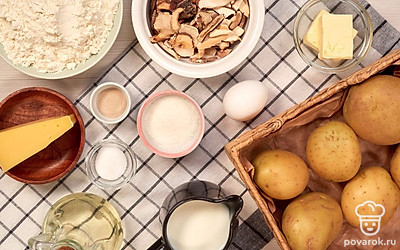 Сушеные грибы залейте холодной кипяченой водой и оставьте на 2 часа. После этого воду слейте, грибы мелко нарежьте. Картофель помойте и очистите. Разогрейте духовку до 190 градусов. Сыр натрите на крупной терке.