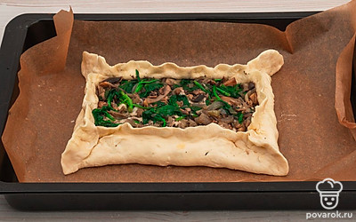 Выложите пирог на противень с пекарской бумагой и смажьте тесто яичным желтком.