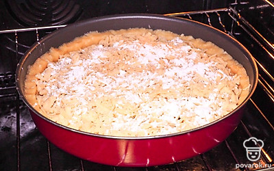 Поставьте пирог запекаться в духовку. Достаньте замороженную часть теста и натрите на крупной терке, заполняя всю поверхность джема. Сверху присыпьте 1 ч.л. сахарного песка для получения более аппетитной и румяной карамельной корочки. Поставьте форму в предварительно разогретую до 180 градусов духовку на 35-40 минут.