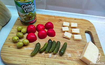 Сыр нарежьте квадратиками. Помидор разрежьте пополам. Пикули и оливки оставьте целыми. Если используете корнишоны, разрежьте их на несколько частей. 