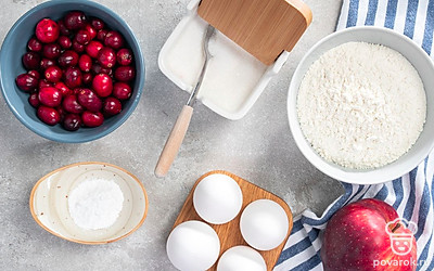 Переберите и промойте клюкву. Вымойте яблоки, очистите от кожуры и семян, нарежьте дольками. Яйца помойте и разбейте в глубокую миску. Подготовьте миксер, форму для выпечки и пергамент. Разогрейте духовку до 180 градусов.