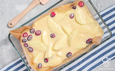 Приготовьте пирог. Вмешайте в тесто яблоки и клюкву. Застелите форму для выпечки пергаментом, залейте в нее тесто. Поставьте пирог в духовку на 35 минут.