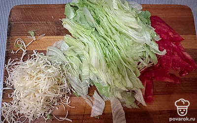 Помидор помойте и нарежьте соломкой. Салат айсберг измельчите, сыр натрите на мелкой терке.