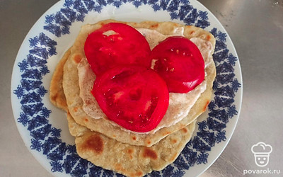 Выложите по 2-3 ломтика помидора. Сложите лепешку пополам.