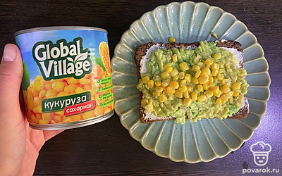 Переложите пюре из авокадо на хлеб, смазанный творожным сыром. Сверху равномерно выложите кукурузу.