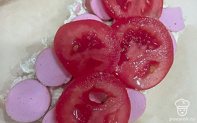 Выложите на чиабатту сосиски и кружки помидора.