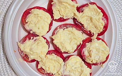 Дольки помидоров смажьте получившейся майонезно-сырной смесью.