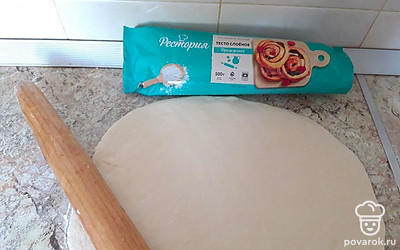 Слоеное дрожжевое тесто раскатайте в пласт толщиной 5 миллиметров, придайте ему форму круга. Переложите тесто на противень или в форму для пиццы, застеленную силиконизированной бумагой для выпечки (пергамент).