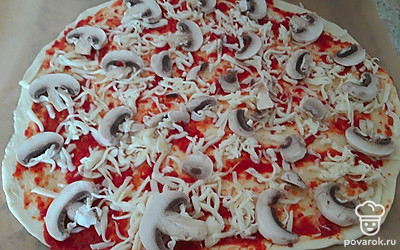 Выложите половину тертого сыра. Измельченный чеснок и грибы равномерно распределите по тесту.