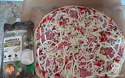 Выложите майонез тонкой струйкой, равномерно распределите оставшийся тертый сыр. 