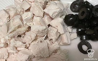 Нарежьте вареное куриное филе и маслины.