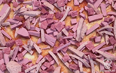 Колбасу всех видов нарежьте соломкой и равномерно выложите на основу пиццы.