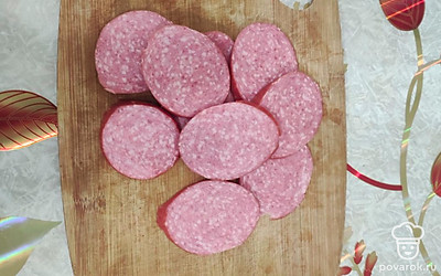 Копченую колбасу очистить от кожуры. Нарезать тонкими кольцами. 