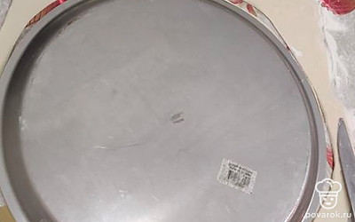 На раскатанное тесто положить форму для выпечки пиццы, вырезать круг. 