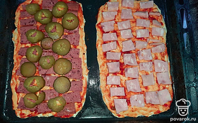 Смазываем основания пиццы томатным соусом. Нарезаем тонкими ломтиками колбасные изделия и овощи, укладываем их на тесто.
