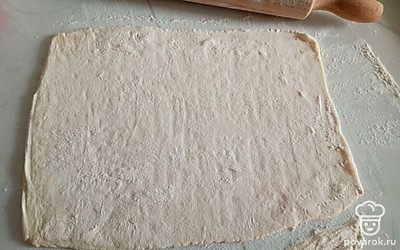 Тесто достаньте из морозилки заранее и раскатайте, присыпая мукой. Противень смажьте растительным маслом и выложите тесто.