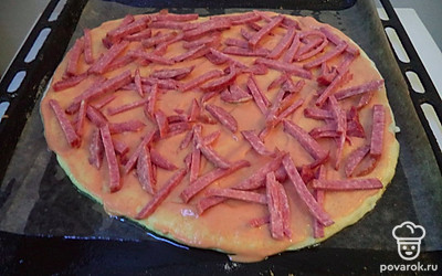 Тесто сверху промазать приготовленным соусом. Выложить колбасу. 