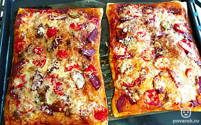 Готовую пицу достаньте из духовки, дайте немного остыть и нарезайте на кусочки.