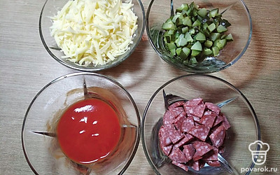 Включаем духовку на 180 градусов. Нарезаем колбасу и огурцы. На крупной тёрке натираем сыр. В томатную пасту добавляем 1,5 столовые ложки воды и перемешиваем.
