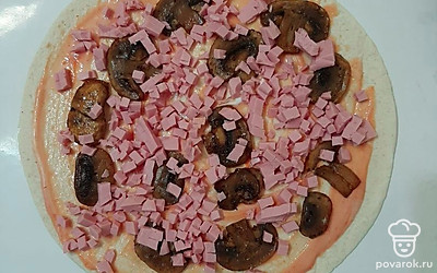 Вареную колбасу нарезать маленькими кубикам, выложить на основу.