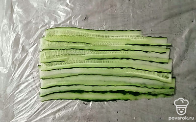 Свежий огурец хорошо помойте. Овощечисткой нарежьте овощ тонкими слайсами. Уложите немного внахлест друг на друга. 