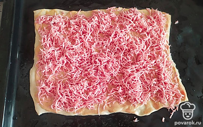 Натираем колбасу на тёрке и кладём сверху заготовленного теста. Можно и нарезать, но мне так нравится больше.