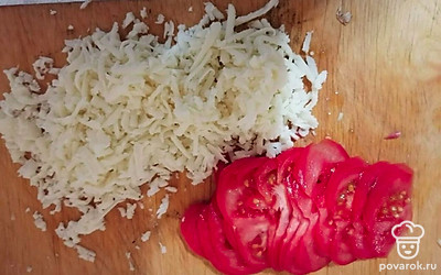 Сыр натереть на крупной терке, помидор порезать тонкими кружками.