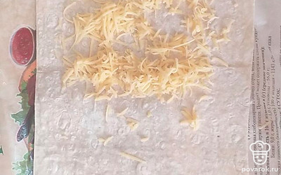 На одну половинку лаваша натереть сыр, закрыть второй половинкой.