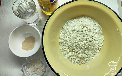 В муку добавьте сухие дрожжи и соль. Влейте воду и перемешайте. 
В конце добавьте растительное масло. 