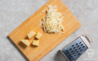 Постелите лаваш на антипригарную сковороду. Часть сыра нарежьте на 4 крупных ломтика, а оставшийся — натрите на средней терке. 