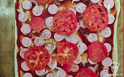 Готовим начинку. Сосиски и помидоры нарезаем кружочками, лук — полукольцами, маслины тоже режем кружочками. Выкладываем начинку на основу. Солим и перчим по вкусу. Можно добавить сушеные прованские травы.