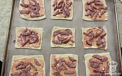 Поверх соуса выложите брусочки копченой колбасы. 