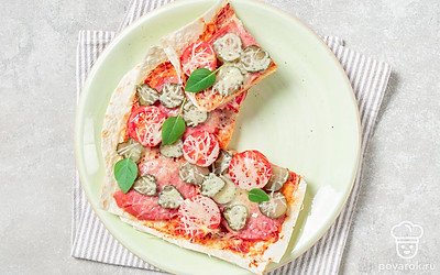 Готовую пиццу выложите на тарелку или деревянную дощечку и разрежьте на порции. Украсьте блюдо веточками базилика и подайте его к столу.