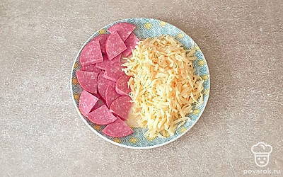 Колбасу нашинкуйте кусочками, а сыр натрите на крупной терке.