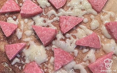 Сверху выкладываем мелко нарезанные квадратики сервелата.