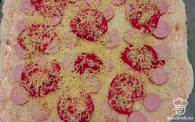 Выложим нарезанные кружочками сосиски и помидоры, посыпаем сыром. Ставим выпекаться в разогретую до 180 градусов духовку. Пицца печется около 30 минут. Готовность проверяем деревянной шпажкой: если она сухая, то пицца готова.