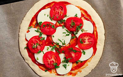 Базилик мелко покрошите, выложите на основу. Отправьте пиццу в духовку на 20 минут.