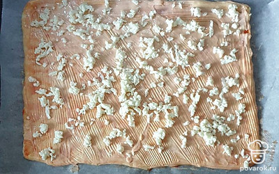 Приготовьте тесто, раскатайте его в пласт нужной формы и выложите на противень. Смажьте его майонезом, сверху посыпьте тертым сыром.