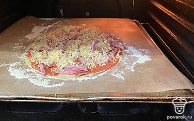 Затем переместите пергаментную бумагу с пиццей на форму для выпекания, отправьте ее выпекаться в духовку на 25 минут при 180 градусах.