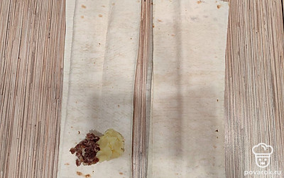 Нарежьте лаваш на прямоугольные полоски шириной примерно в 10 сантиметров. В самом низу выложите начинку из картофельного пюре и фарша.