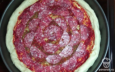 Тесто распределить по форме и сделать бортики. Томатную пасту распределить по дну, добавить специи: укроп, петрушку и паприку. Сверху выложить колбасу.