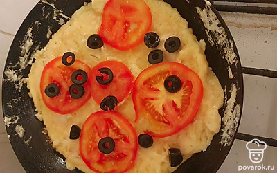 Выложить тесто на сковороду. Жарить под крышкой 5 минут. После выложить помидоры и маслины.