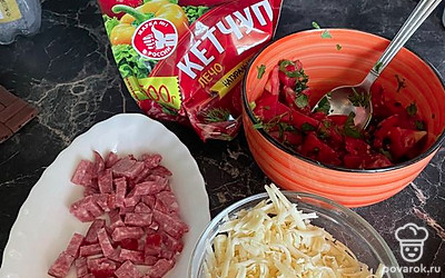 Разморозьте тесто, нарежьте на квадраты. Подготовьте начинку. Нарежьте колбаску, помидоры, натрите сыр на терке.