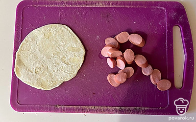 Тесто раскатайте в тонкий пласт, а сосиску нарежьте, как показано на фото. 