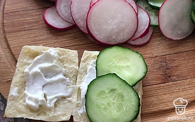 Смажьте обе части выпечки любым соусом или творожным сыром. Можете ничего не добавлять. Смотрите на свой вкус и наличие продуктов. Выложите огурец на одну часть.