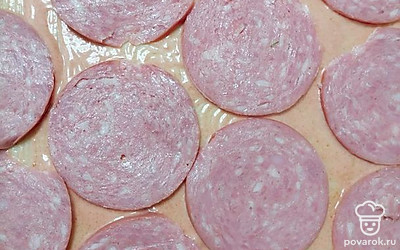 Порежьте колбасу кружочками или соломкой, как вам больше нравится. Закиньте ее на тесто.