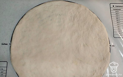 Раскатываем тесто руками в круг диаметром 30 сантиметров. Я использую силиконовый коврик.