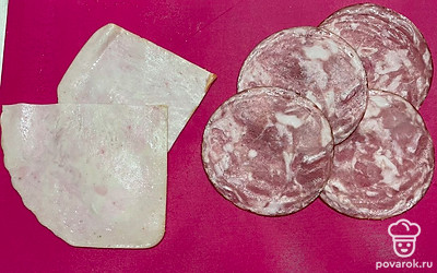 Нарежьте ветчину на тонкие пластинки, а колбасу на тонкие кружочки.