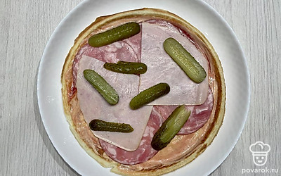 Выложите ветчину, колбасу и огурцы на корж.