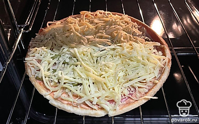 Посыпьте сверху сыром. Выложите пиццу на противень или на решетку, запекайте в разогретой до 180 градусов духовке 15 минут.